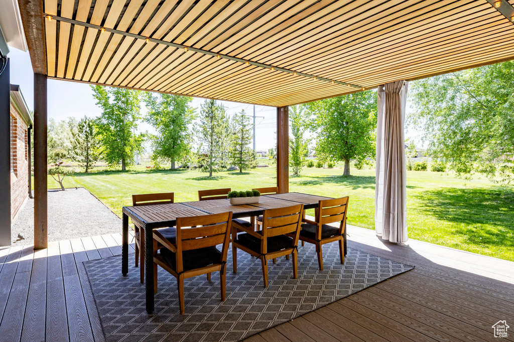 Wooden deck featuring outdoor dining space and a lawn