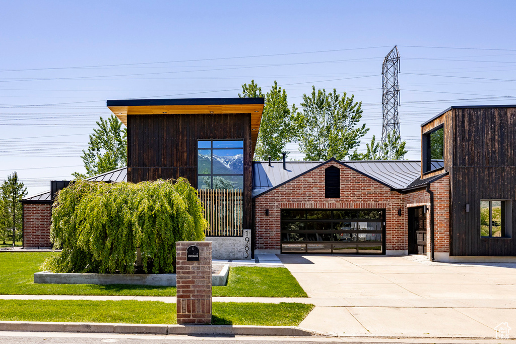 Contemporary house featuring a standing seam roof, metal roof, and driveway