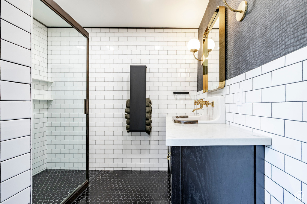 Bathroom featuring tile walls, a tile shower, and vanity