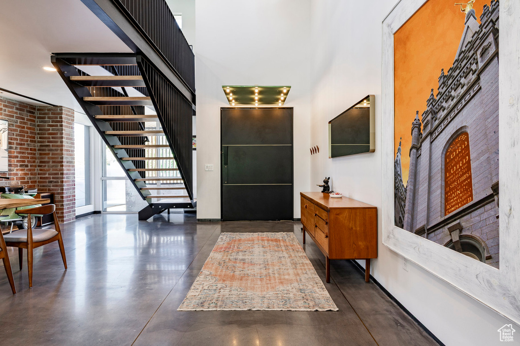 Entryway with a towering ceiling, concrete flooring, stairs, and baseboards