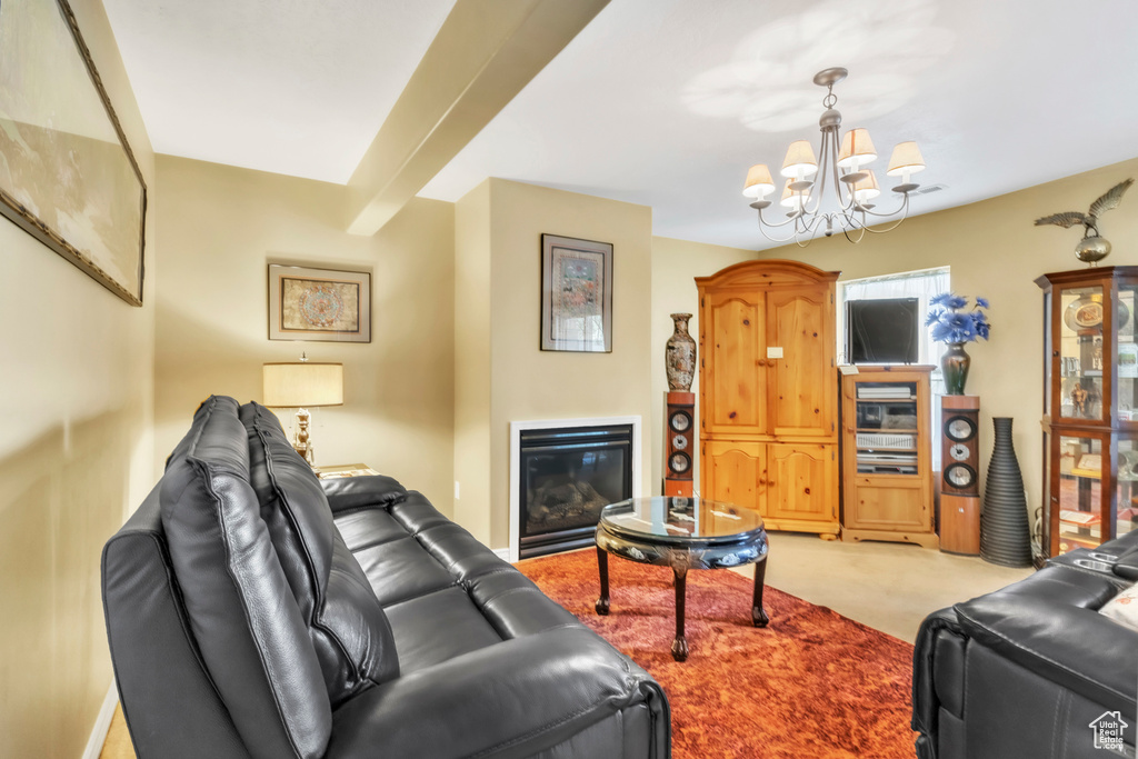 Living room featuring a chandelier, light carpet, and a glass covered fireplace