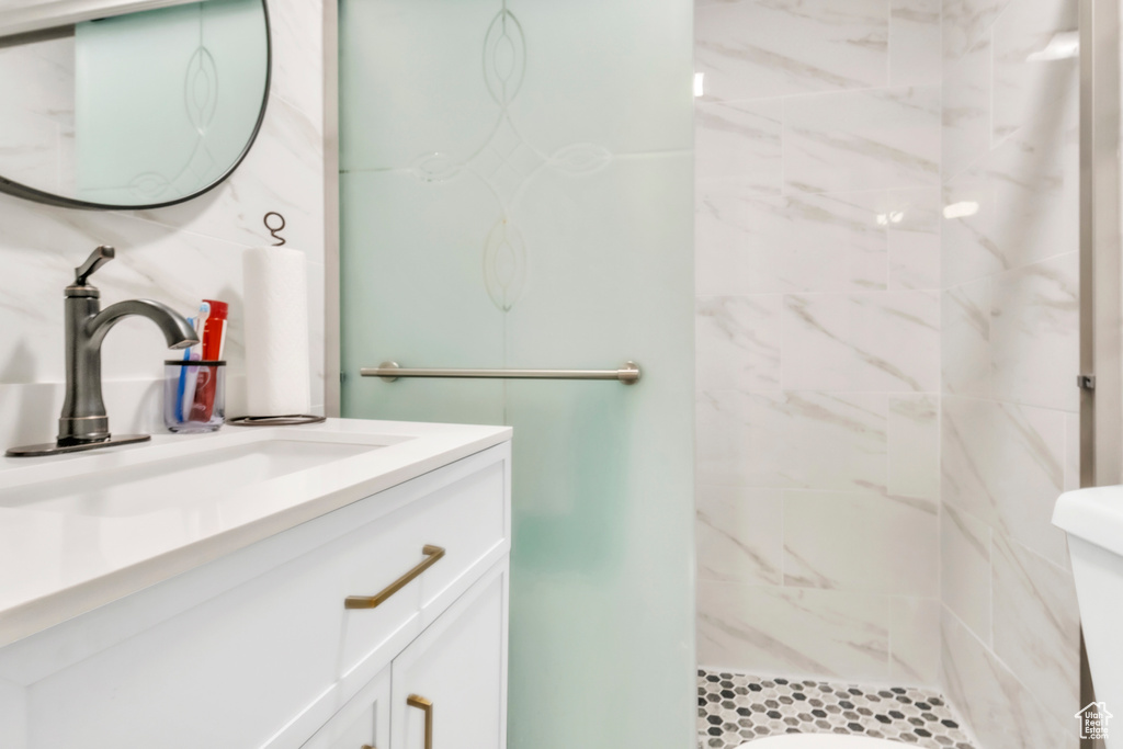 Bathroom featuring vanity, a tile shower, and toilet