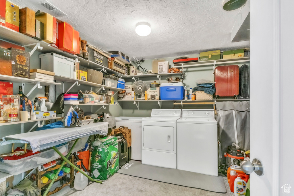 Laundry room featuring washer and clothes dryer, a textured ceiling, and carpet