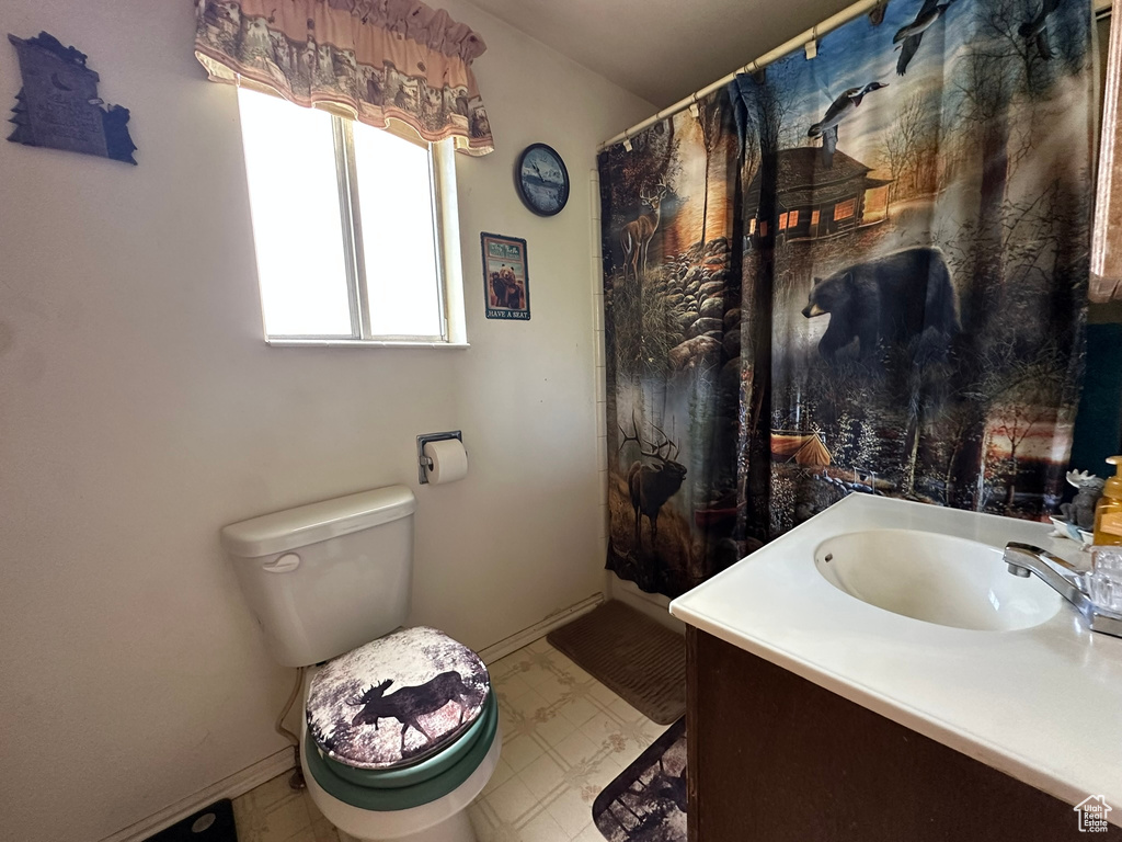 Bathroom featuring vanity, toilet, baseboards, and tile patterned floors