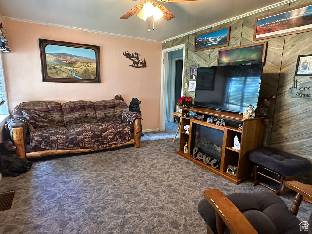 Carpeted living area featuring ceiling fan and crown molding