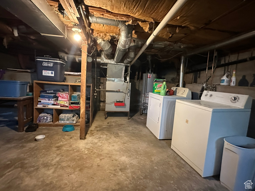Unfinished basement featuring washing machine and clothes dryer, gas water heater, and heating unit