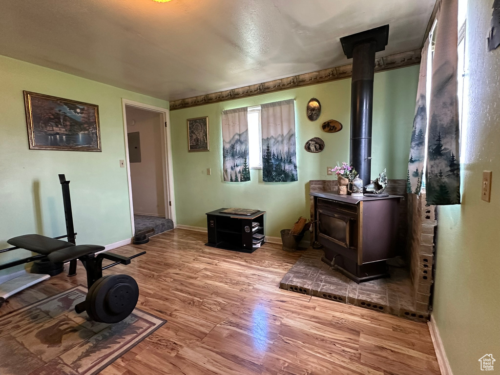 Exercise room with a wood stove, wood finished floors, and baseboards