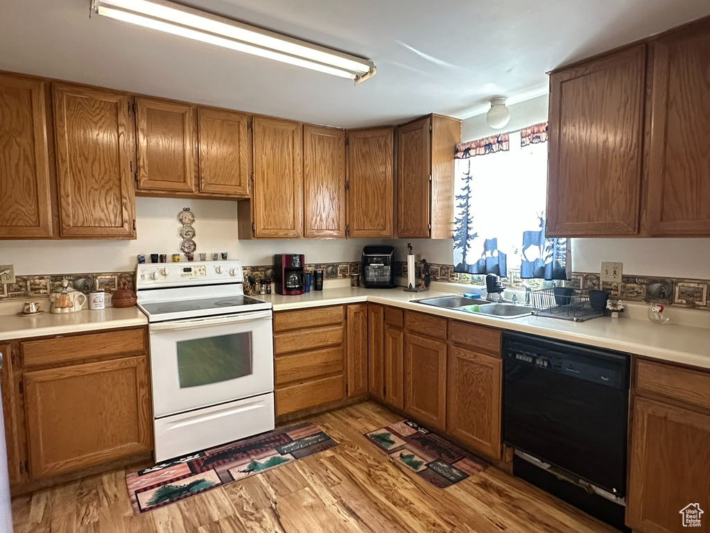 Kitchen with white electric range, dishwasher, a sink, and light wood-style floors