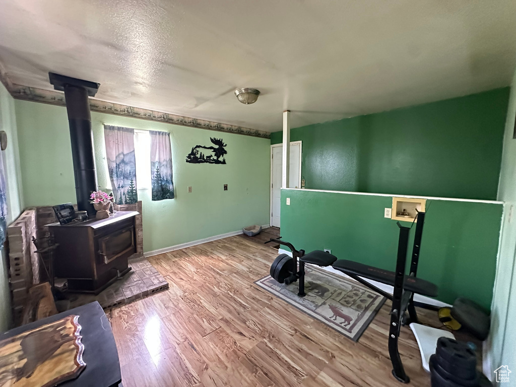 Exercise area with a wood stove, wood finished floors, and baseboards