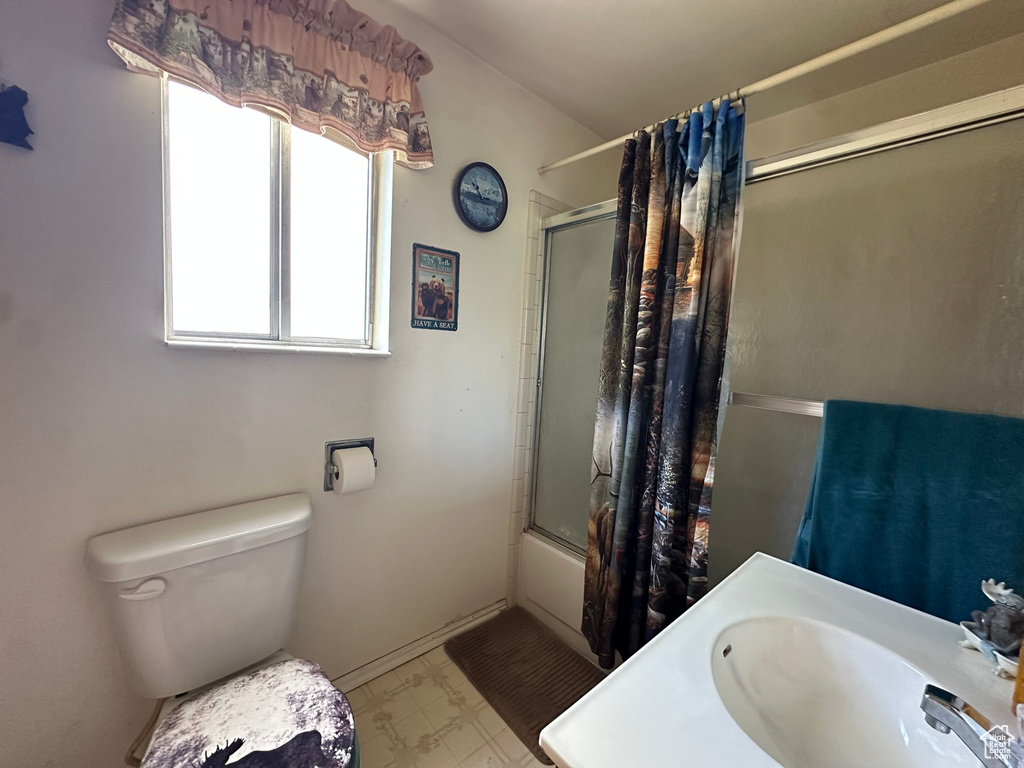 Full bath featuring shower / bath combination with glass door, a sink, and toilet