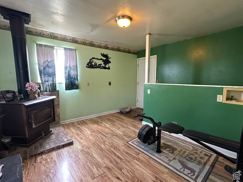Workout room featuring a wood stove, wood finished floors, and baseboards