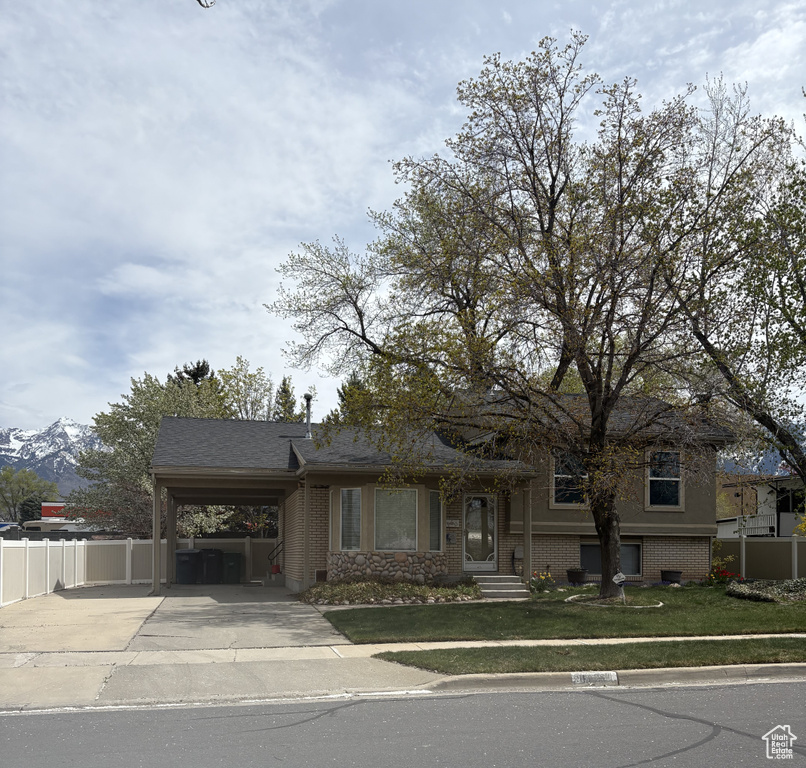 View of front of home featuring driveway, an attached carport, and brick siding