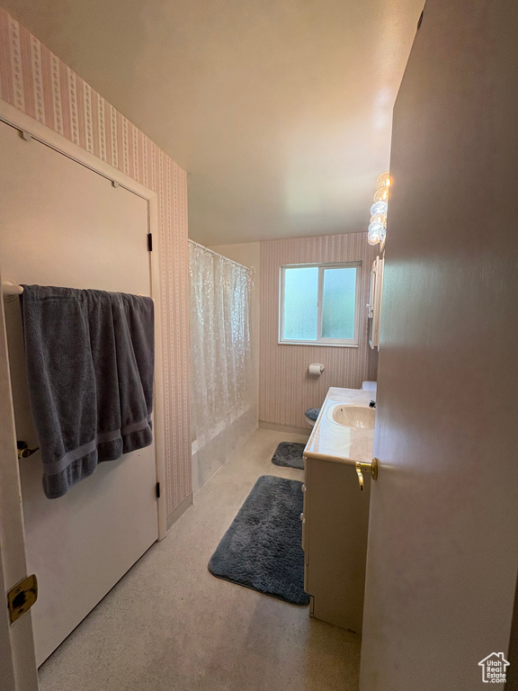 Full bathroom with vanity, wallpapered walls, and curtained shower