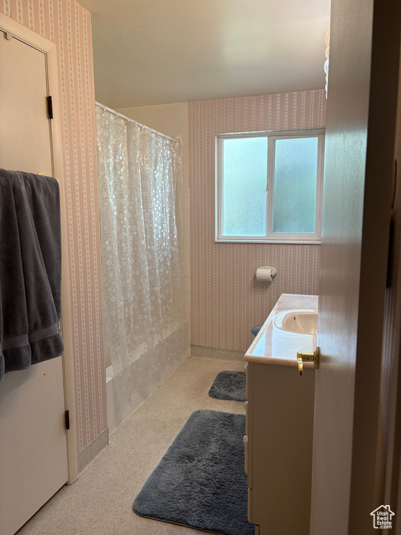 Full bath with wallpapered walls and vanity