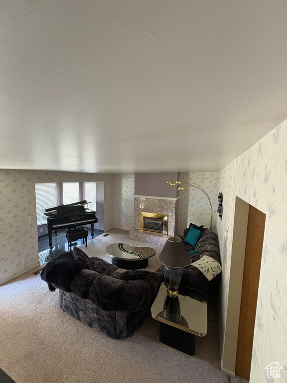 Living room featuring wallpapered walls, a fireplace, and carpet flooring