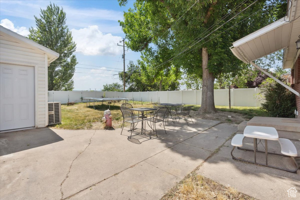 Fenced backyard with a trampoline, a patio area, and outdoor dining space