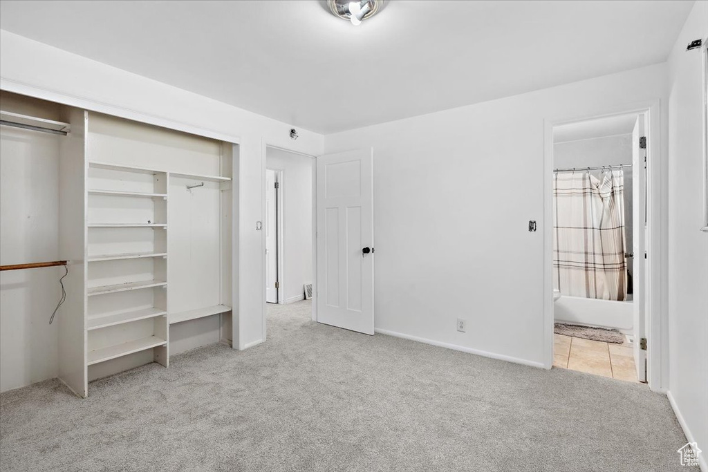 Unfurnished bedroom with carpet floors, a closet, ensuite bath, and baseboards