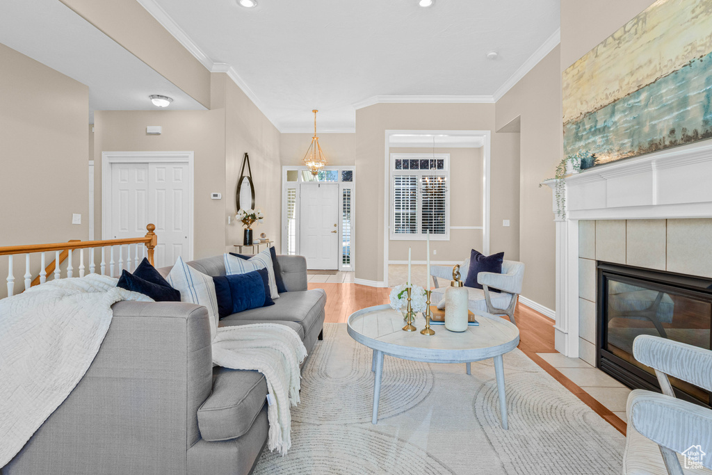 Living area featuring light wood-type flooring, ornamental molding, a tile fireplace, baseboards, and recessed lighting