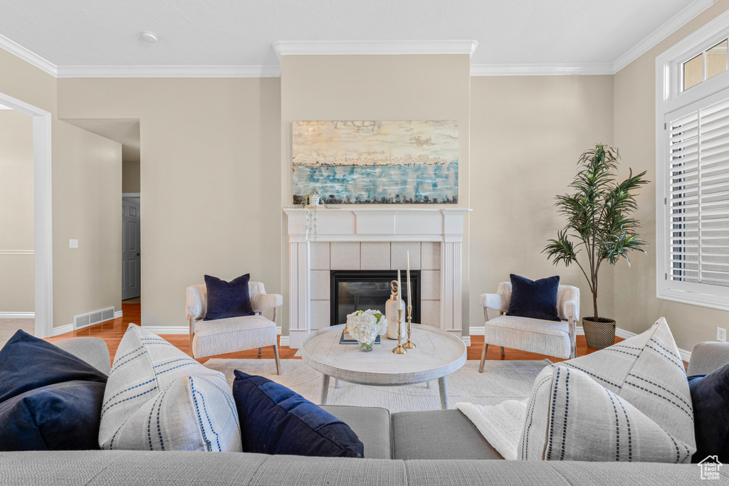 Living room featuring crown molding, wood finished floors, a tile fireplace, and baseboards