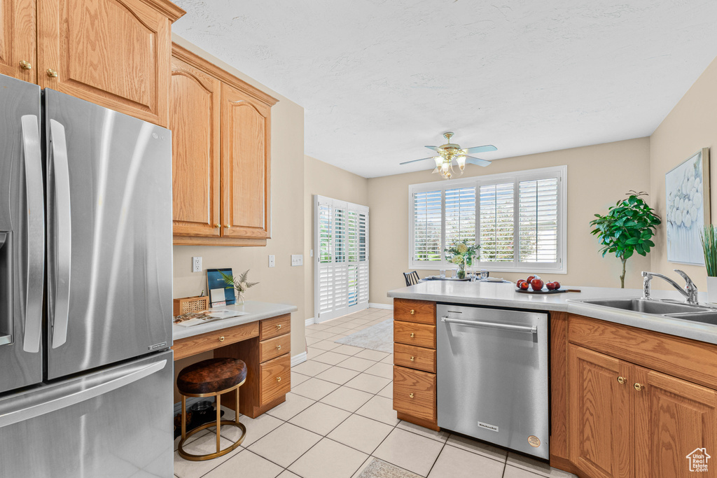 Kitchen featuring appliances with stainless steel finishes, light tile patterned flooring, light countertops, a ceiling fan, and a sink