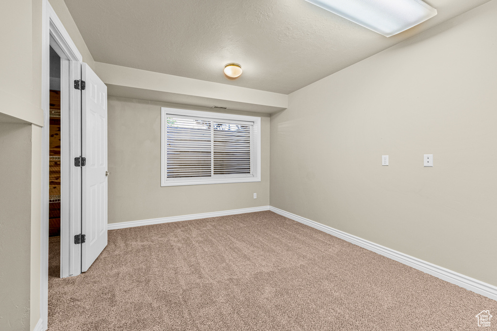Empty room with carpet floors, baseboards, and a textured ceiling