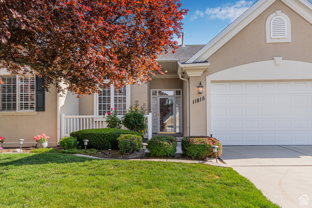 View of front of property with a front yard, stucco siding, driveway, and an attached garage