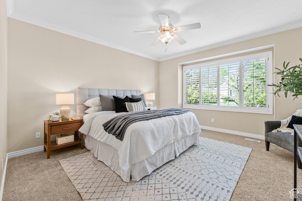 Bedroom featuring light colored carpet, ornamental molding, baseboards, and ceiling fan