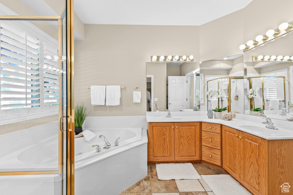 Full bathroom featuring a bath, double vanity, and a stall shower