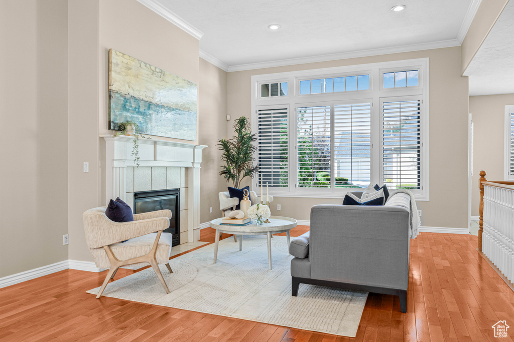 Living room with light wood-style flooring, ornamental molding, a fireplace, baseboards, and recessed lighting
