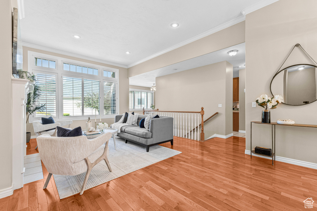 Living room with crown molding, light wood-type flooring, baseboards, recessed lighting, and a chandelier