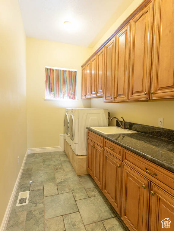 Laundry area with cabinet space, washer and dryer, baseboards, and stone finish flooring