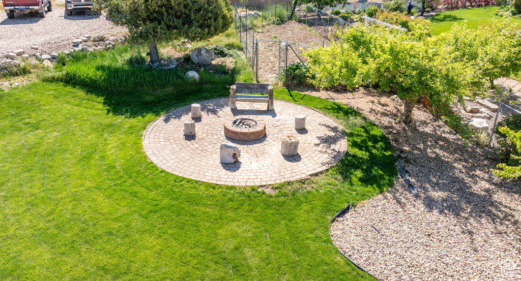 View of grassy yard featuring an outdoor fire pit and a patio
