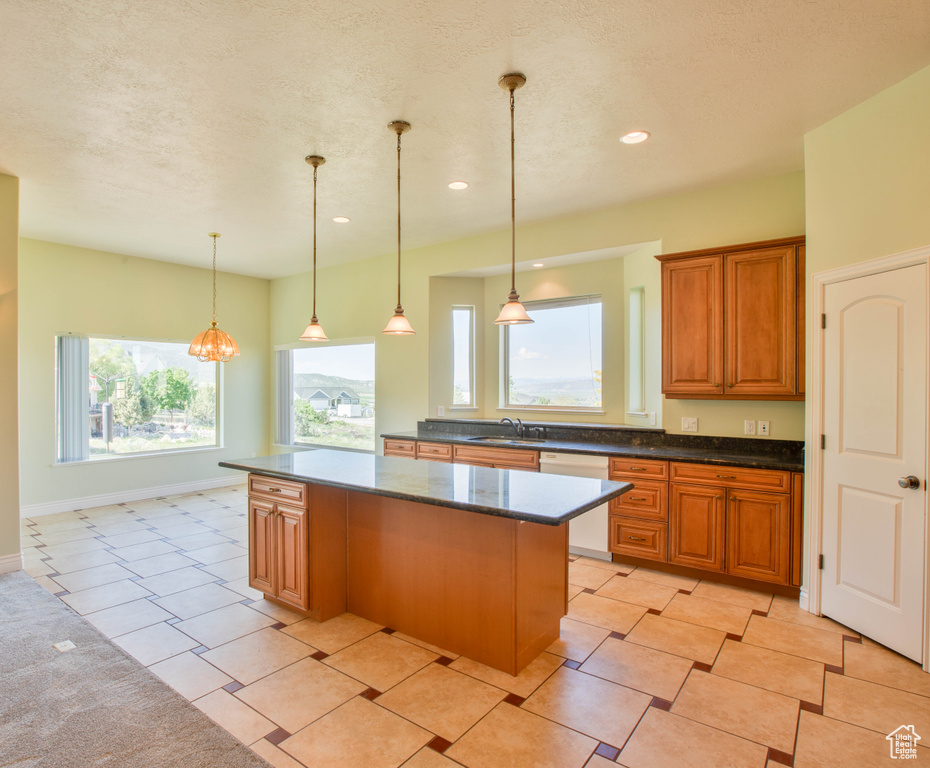 Kitchen with a sink, a center island, brown cabinets, dishwasher, and pendant lighting