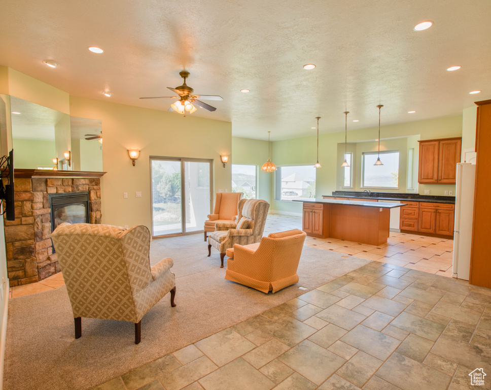Living area featuring recessed lighting, ceiling fan, a stone fireplace, and stone tile flooring