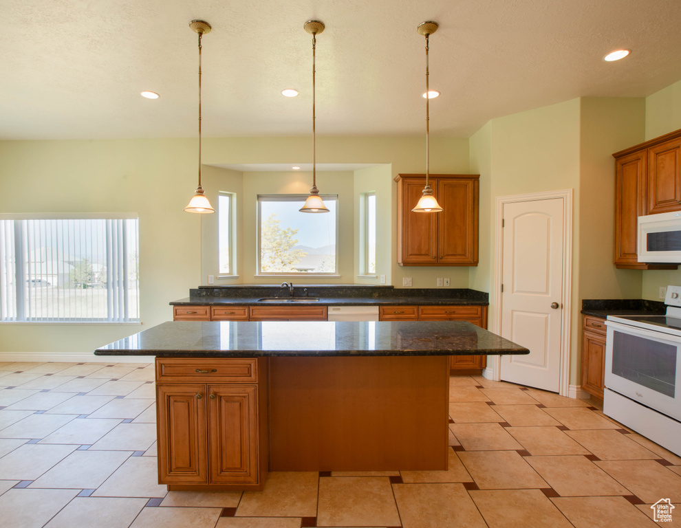 Kitchen with white appliances, a kitchen island, healthy amount of natural light, recessed lighting, and brown cabinetry