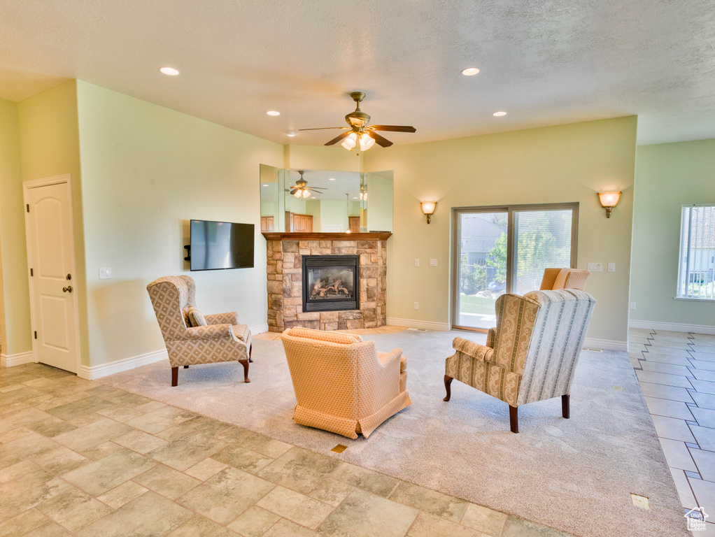 Living area featuring plenty of natural light, baseboards, a stone fireplace, ceiling fan, and recessed lighting