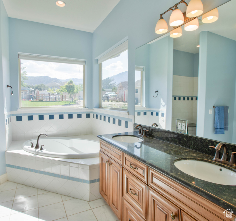 Full bathroom featuring a mountain view, a garden tub, double vanity, and tile patterned flooring