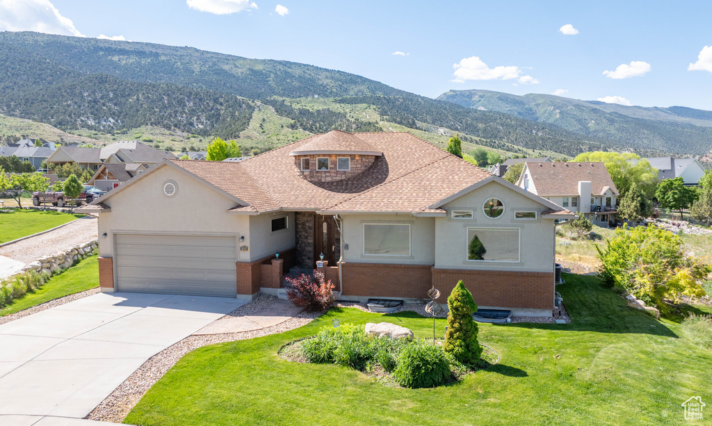 View of front of house with brick siding, an attached garage, a mountain view, and driveway