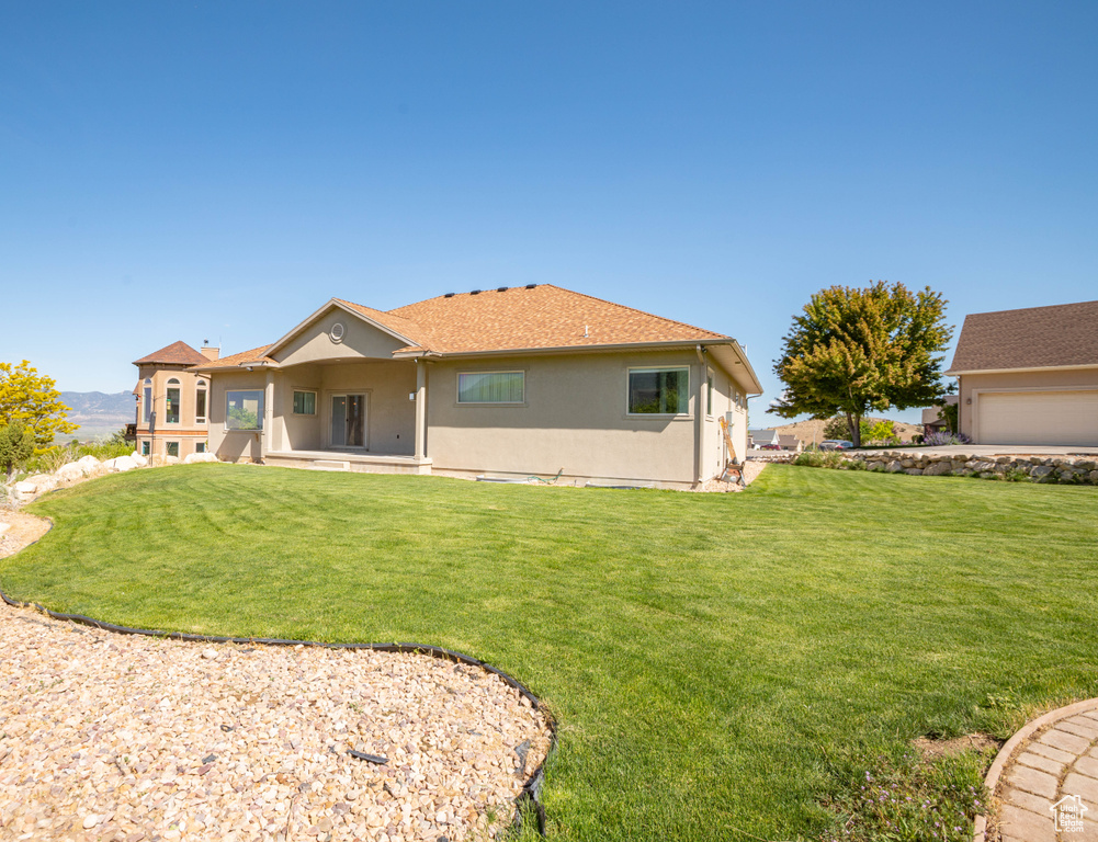 Rear view of house featuring stucco siding and a yard