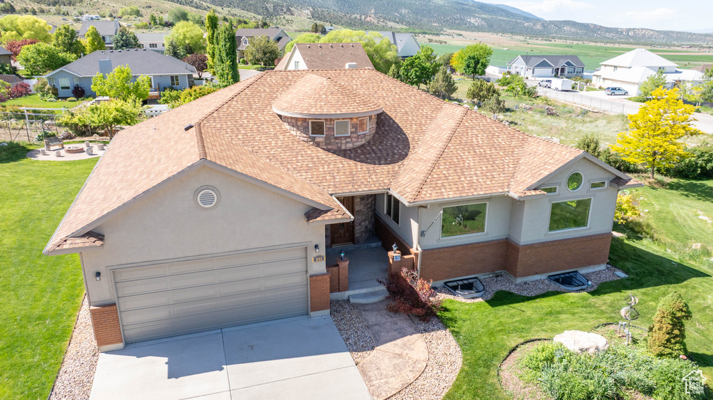 View of front of house featuring driveway, stucco siding, a front lawn, a garage, and a residential view