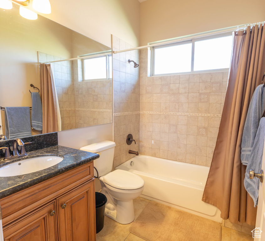 Bathroom featuring shower / bath combo with shower curtain, vanity, toilet, and tile patterned floors