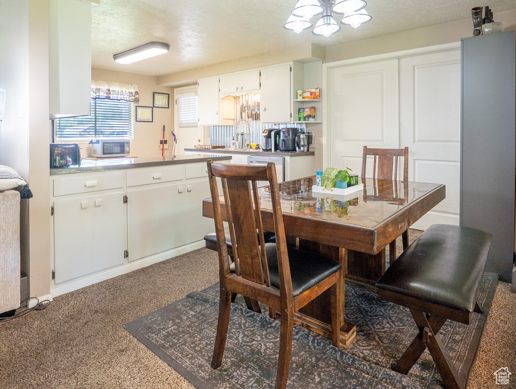 Dining area featuring a chandelier, carpet floors, and a textured ceiling