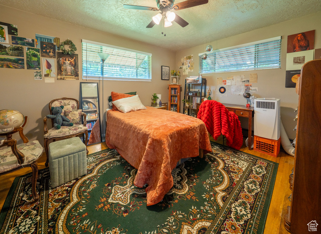 Bedroom featuring a textured ceiling, wood finished floors, and a ceiling fan