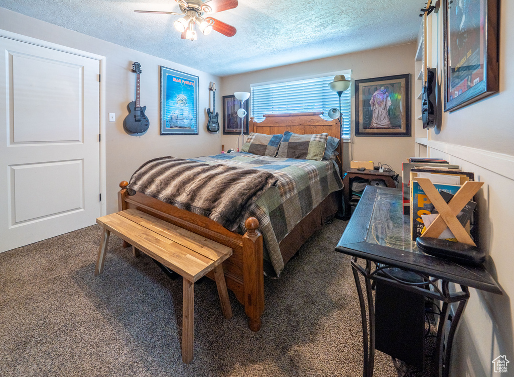 Carpeted bedroom featuring a textured ceiling and ceiling fan