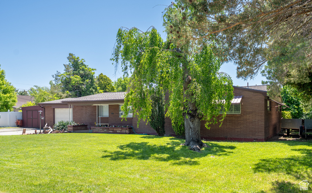Ranch-style home with brick siding, an attached garage, a front lawn, and driveway