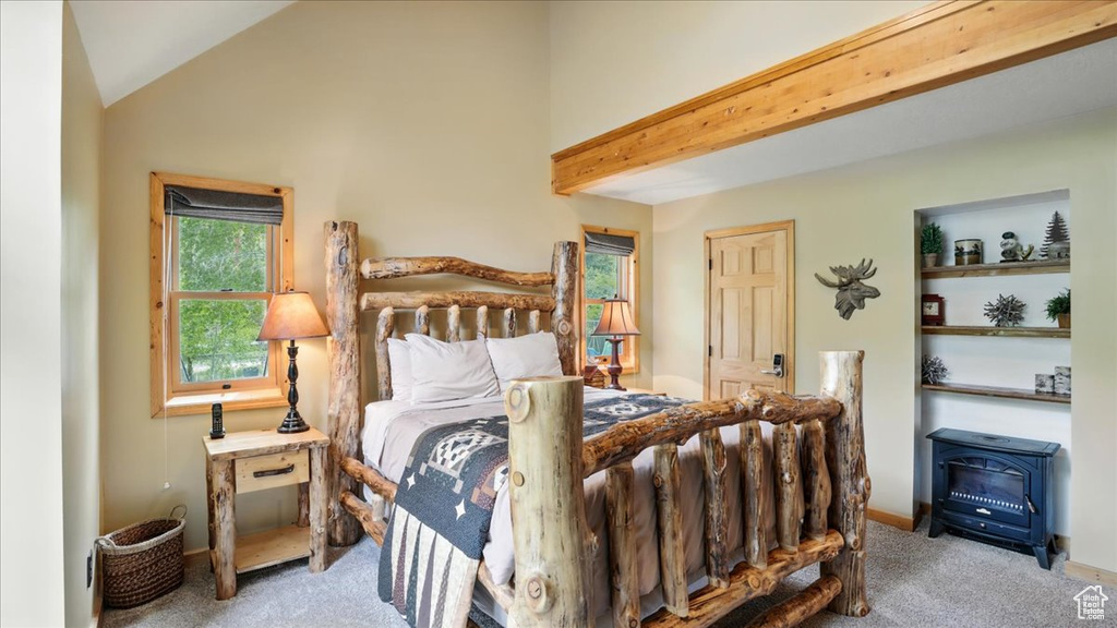 Bedroom with carpet floors, a wood stove, and vaulted ceiling