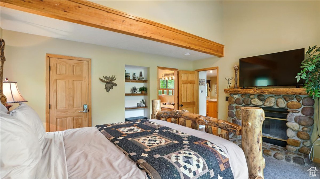 Bedroom featuring beamed ceiling, carpet, and ensuite bath