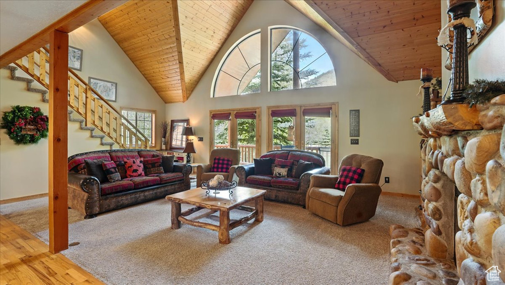 Carpeted living room with stairway, high vaulted ceiling, and wood ceiling