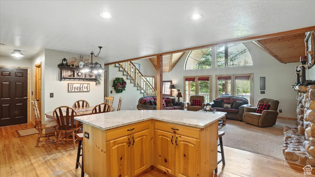 Kitchen with a breakfast bar area, light wood-style floors, open floor plan, lofted ceiling, and a kitchen island