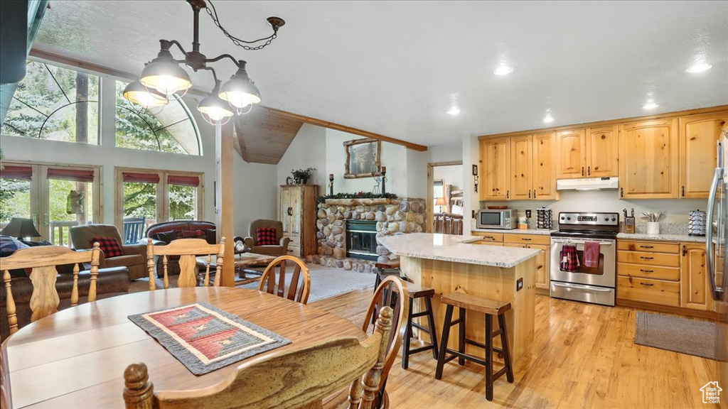 Dining space with a chandelier, healthy amount of natural light, recessed lighting, light wood-style flooring, and a stone fireplace